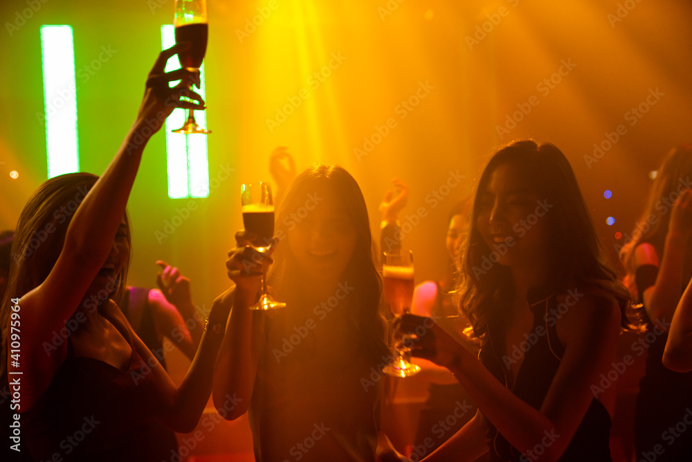 Silhouette image of people dance in disco night club to music from DJ on stage . New year night part