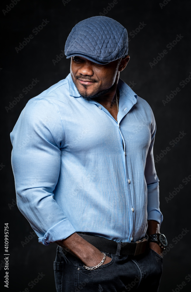 Portrait of a modern young black man smiling with hands in pockets isolated over black background. M