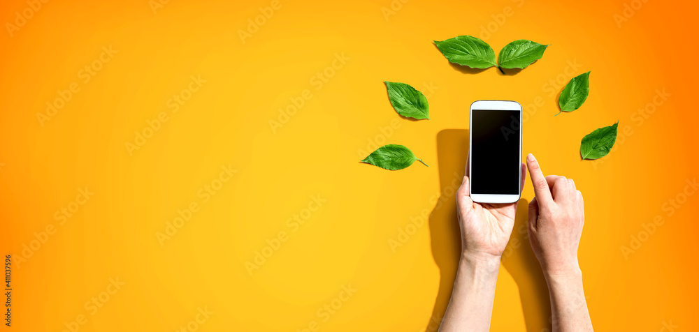 Person holding a smartphone with green leaves