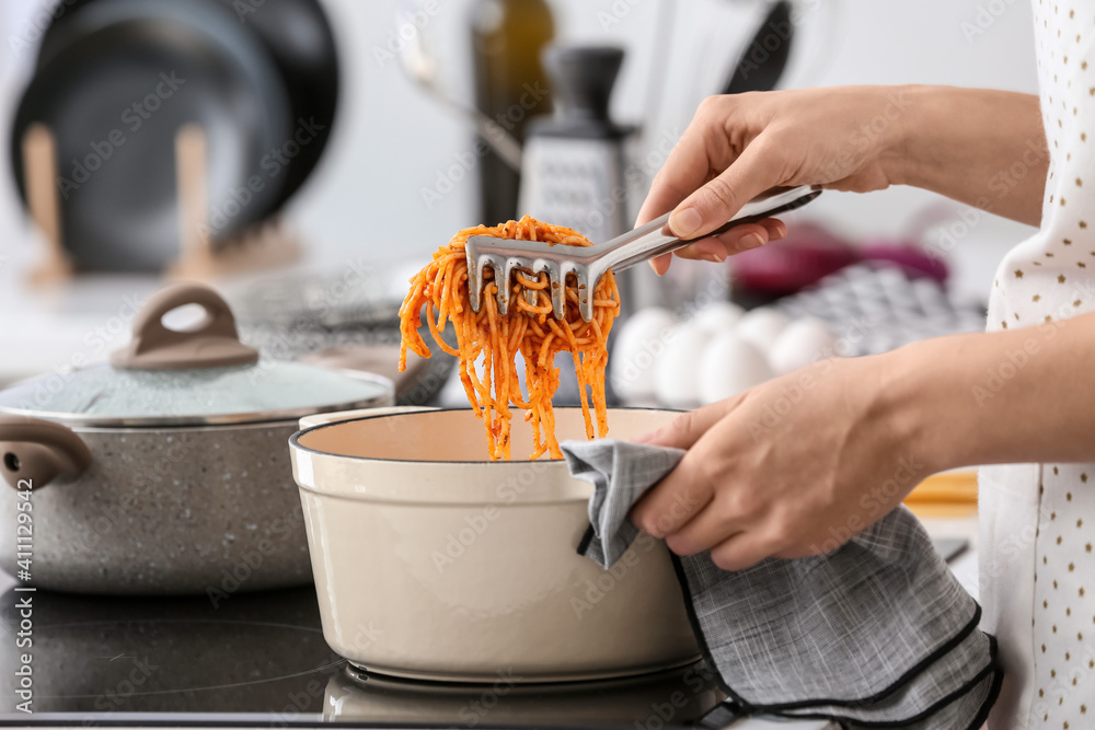 Woman cooking tasty pasta in kitchen