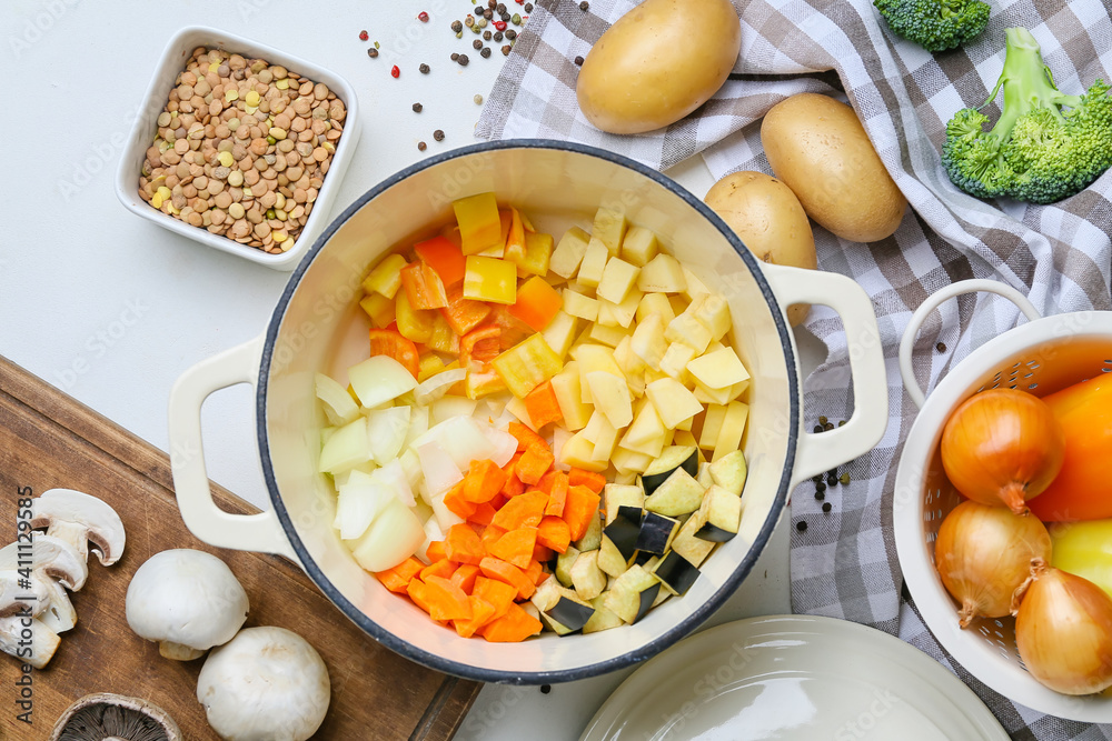 Vegetables in cooking pot on light background