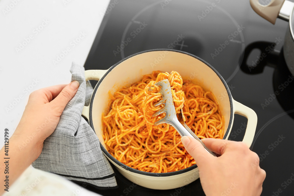 Woman cooking tasty pasta in kitchen