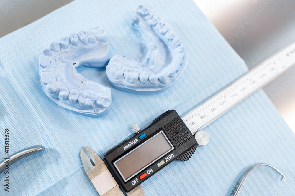 Dental tools and artificial jaw model for the orthodontic treatment lying on the table at the dental