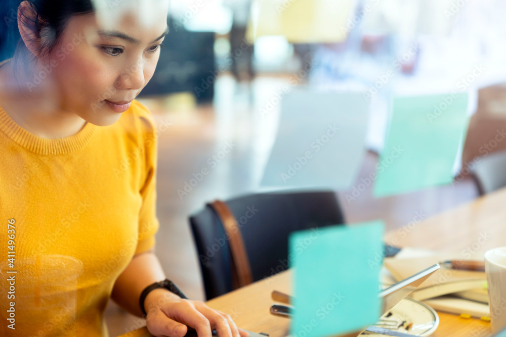 attractive freelance asian female creative person wear casual yellow cloth working with laptop at sh