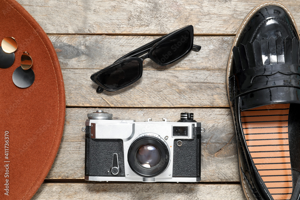 Set of female accessories, photo camera and sunglasses on wooden background