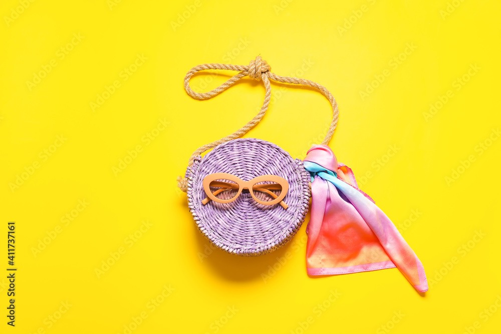 Stylish sunglasses and bag on color background