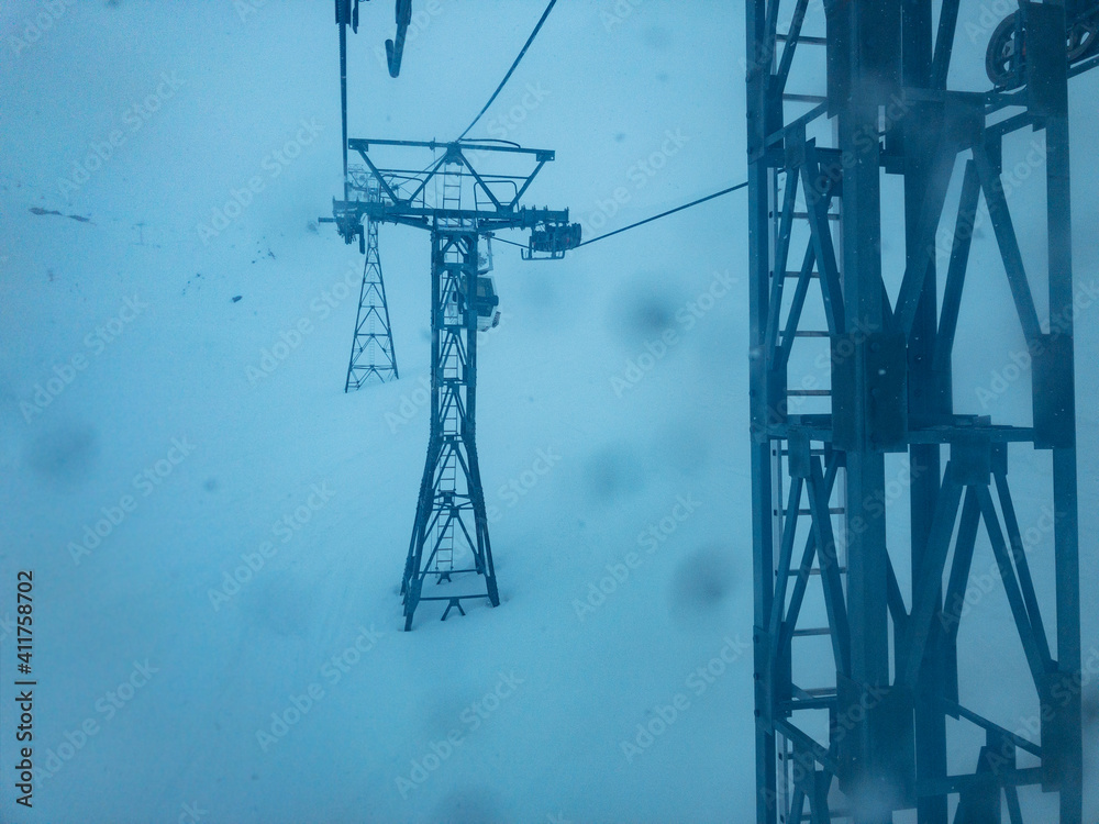 Bad weather on skiing resort - storm and heavy snowfall in the mountains view of ski lift cabin with