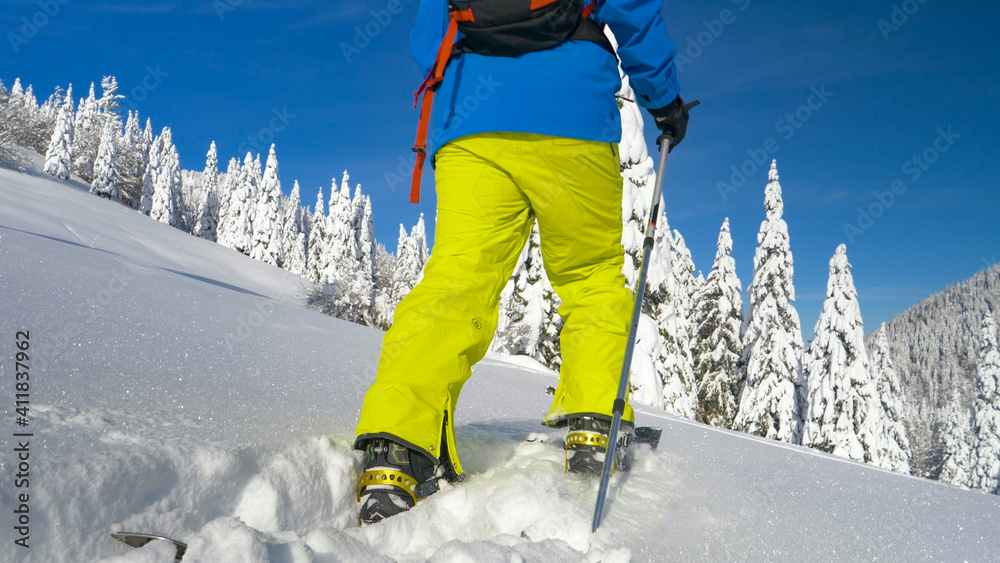 低角度：男滑板手在探索阿尔卑斯山时踩着厚厚的粉雪。