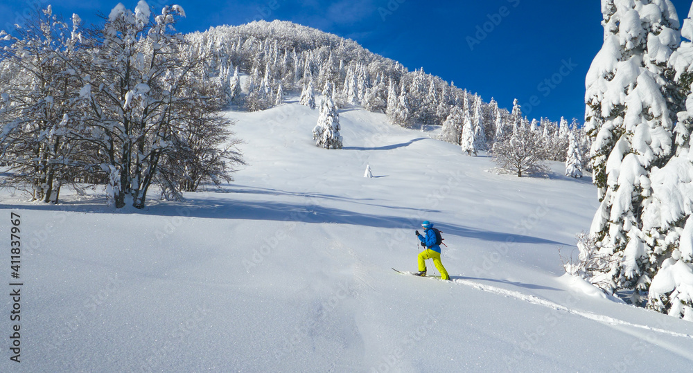 AERIAL: Man hikes in the pristine white countryside to splitboard off piste.