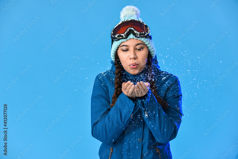 Female snowboarder playing with snow on color background