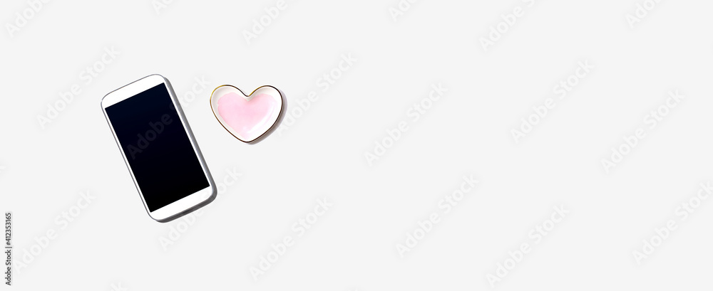 Smartphone with heart shaped dish - flat lay