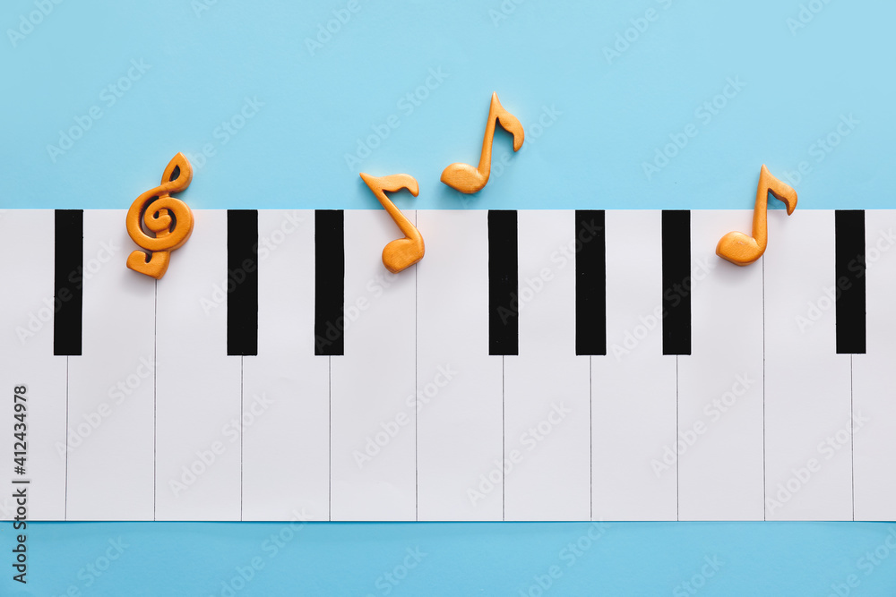 Note signs and piano made of paper on color background