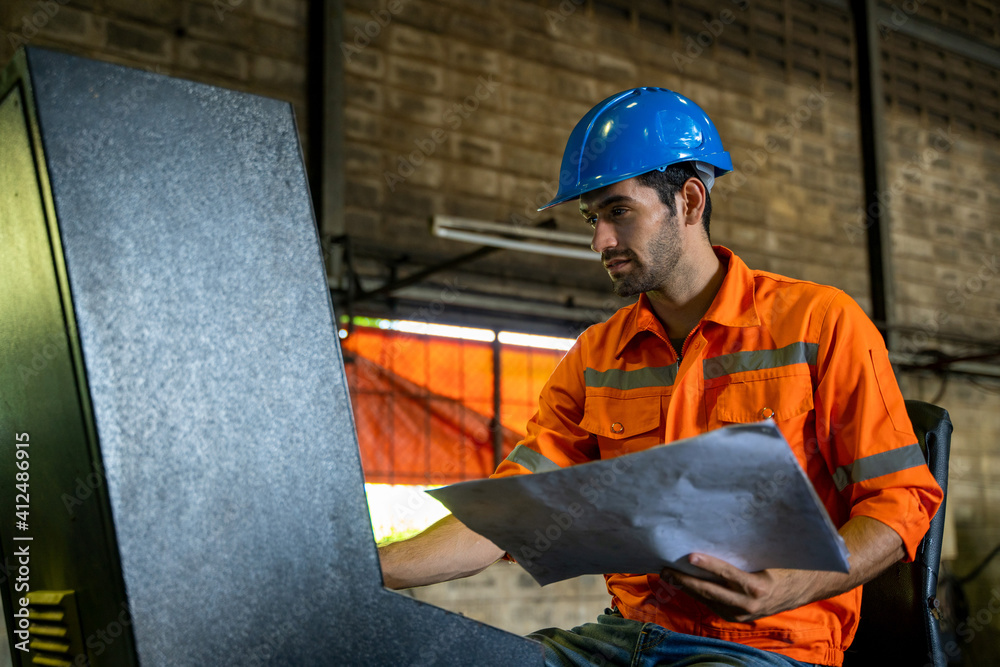 Engineer in factory watching blueprint for the working process.