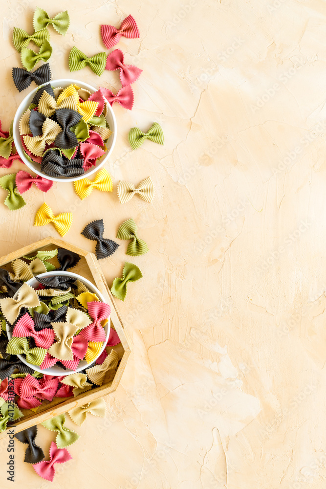 Italian farfalle pasta in bowls. Raw multicolored farfalle pasta, overhead view