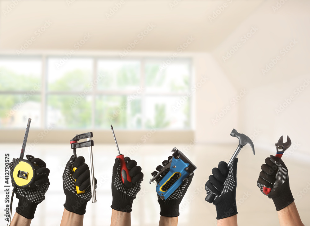 Many hands with different construction tools indoors