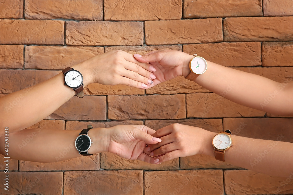 Women with wrist watches shaking hands near brick wall