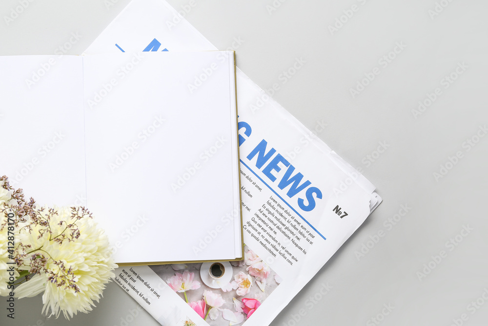 Blank book and newspaper on light background