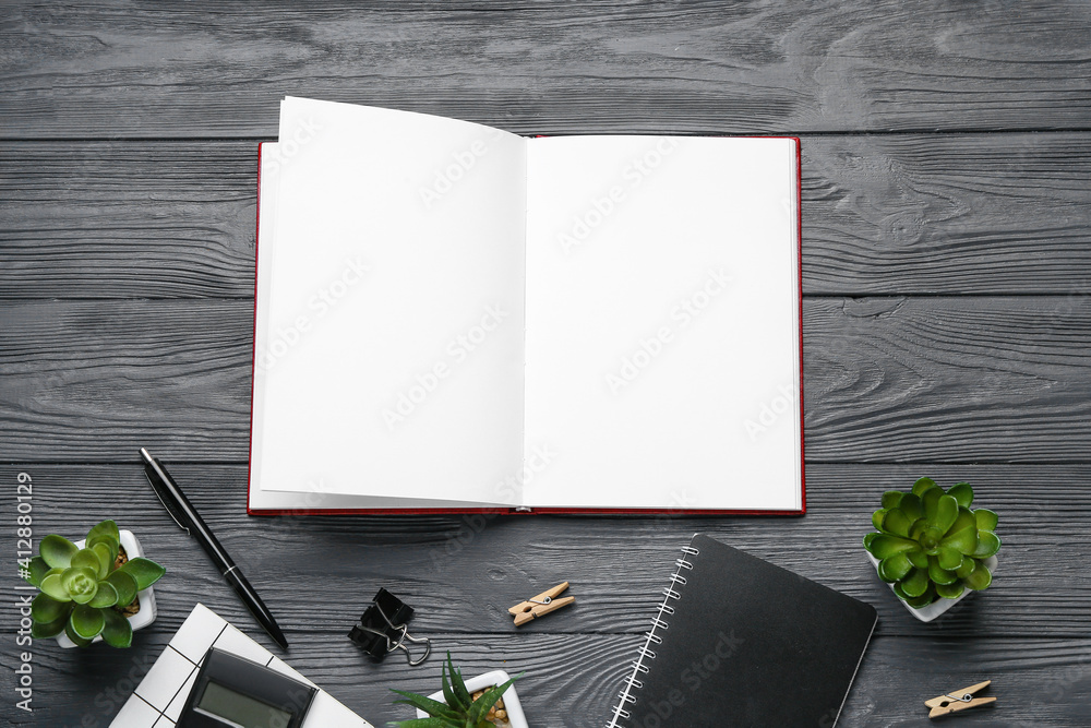 Blank open book and stationery on wooden background