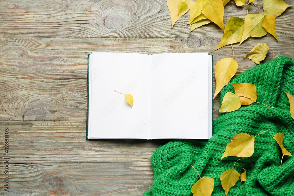 Blank open book and autumn leaves on wooden background