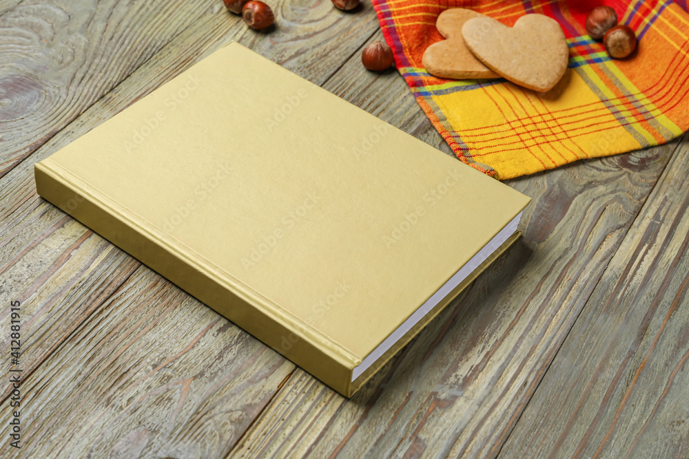 Blank book, cookies and hazelnuts on wooden background