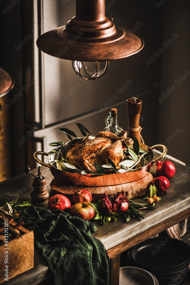 Whole roasted chicken for winter holiday festive dinner in copper roasting tin with spices, herbs an