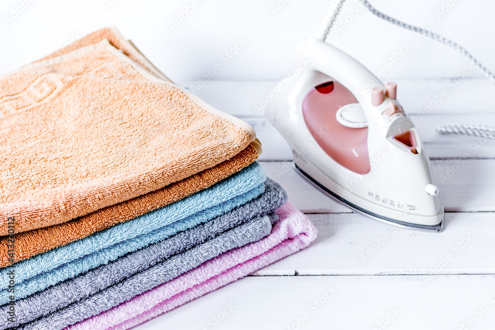 Bath towels stack with iron in laundry light background