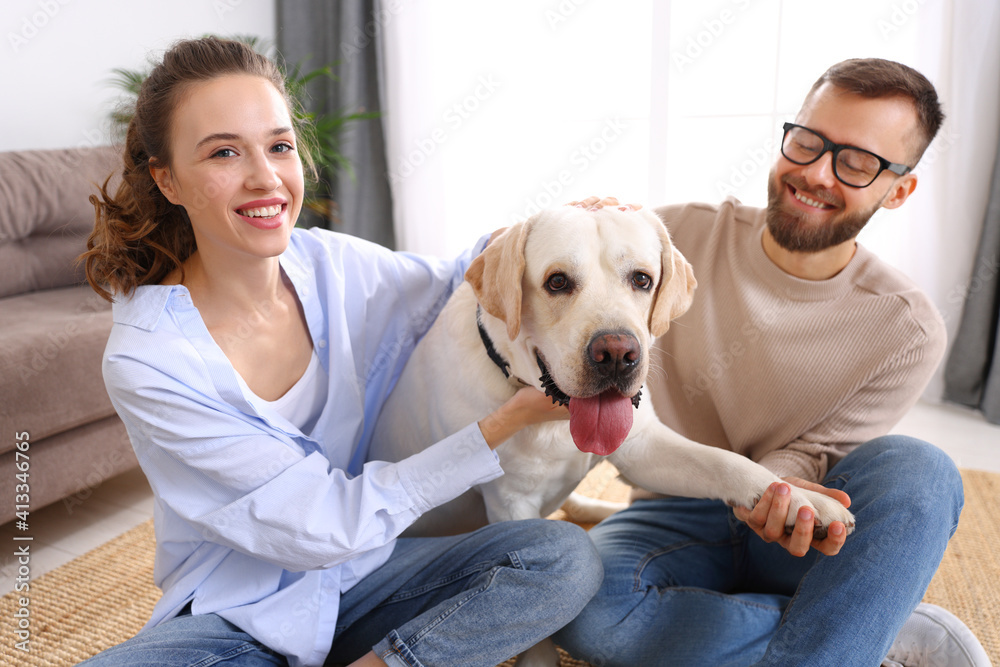 幸福的已婚夫妇在家里和他们最喜欢的宠物狗玩耍