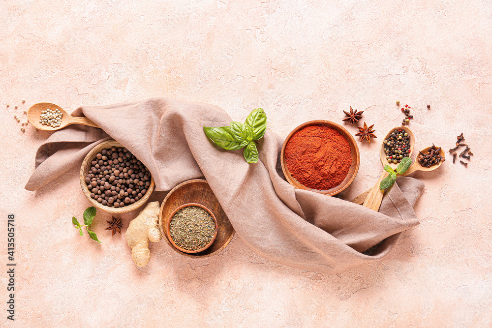 Bowls and spoons with different spices on color background