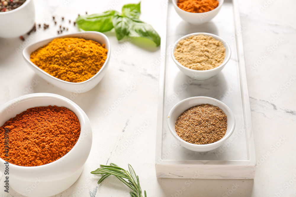 Bowls with different spices on light background