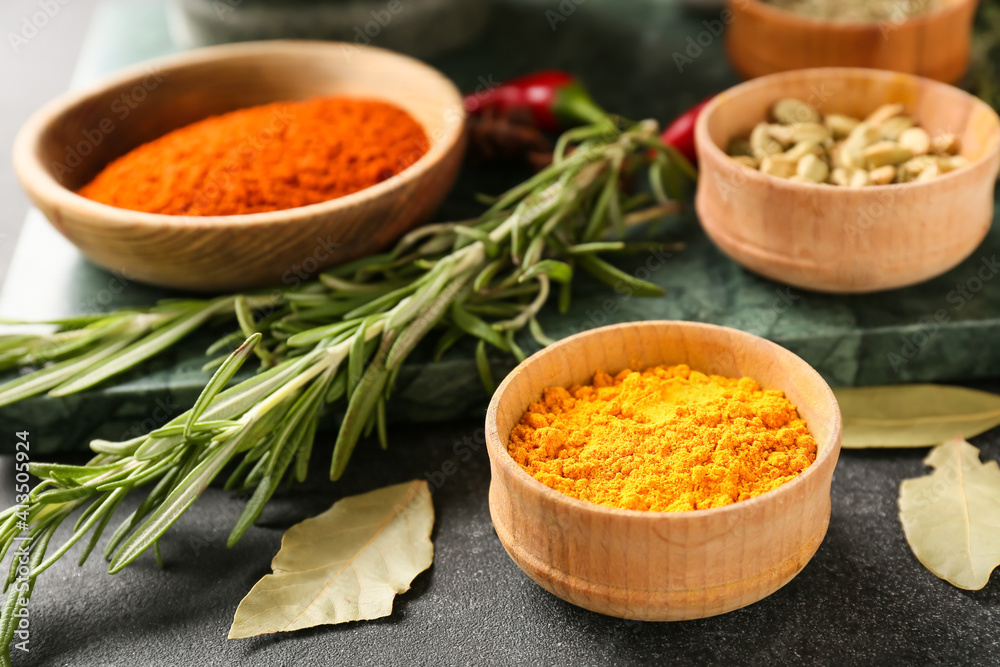 Bowls with different spices on dark background, closeup