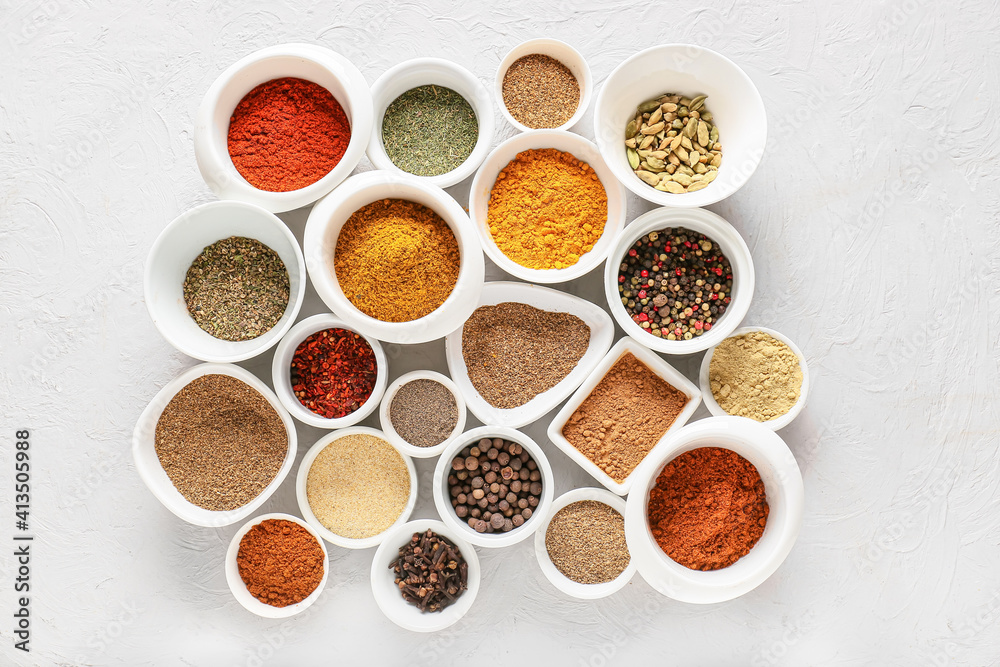 Bowls with different spices on light background