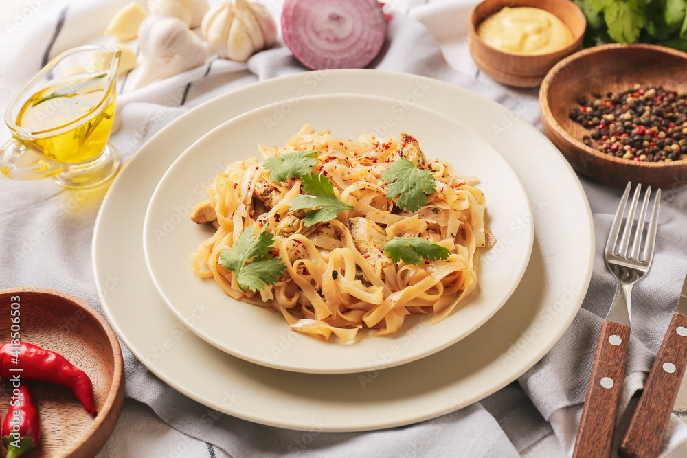 Plate with tasty noodles, chicken and ingredients on table