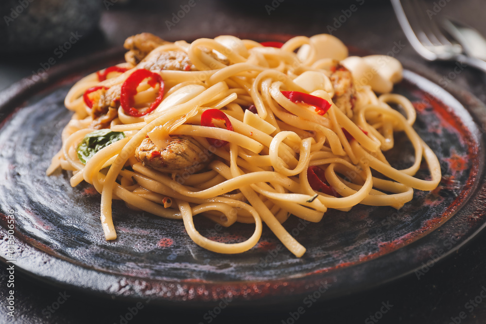 Plate with tasty noodles and chicken on dark background, closeup