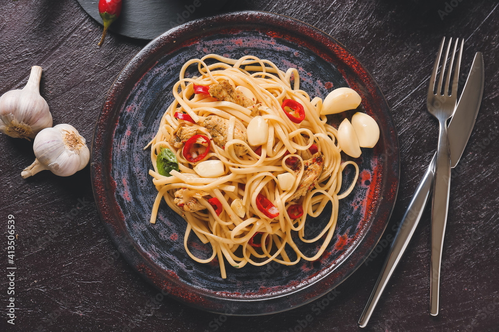 黑色背景下有美味的面条、鸡肉和大蒜的盘子