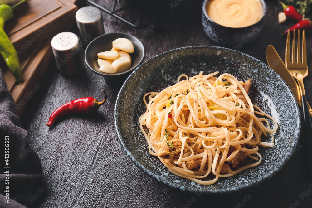 Bowl with tasty noodles and chicken on dark background