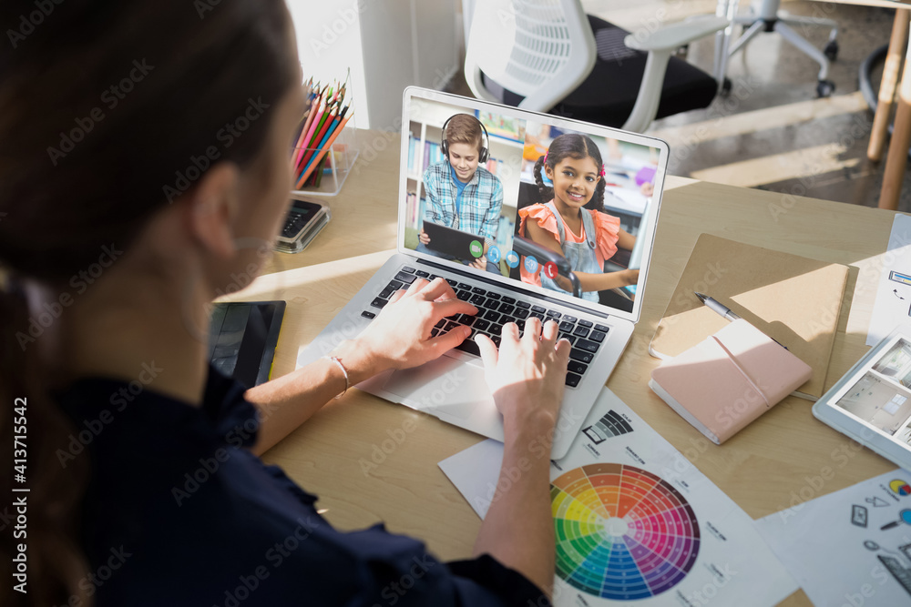 Female teacher having a video conference with male and female students on laptop at school