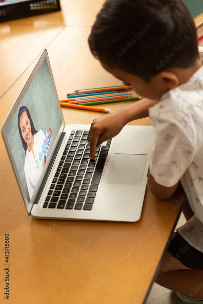 Male student having a video call with female teacher on laptop at school