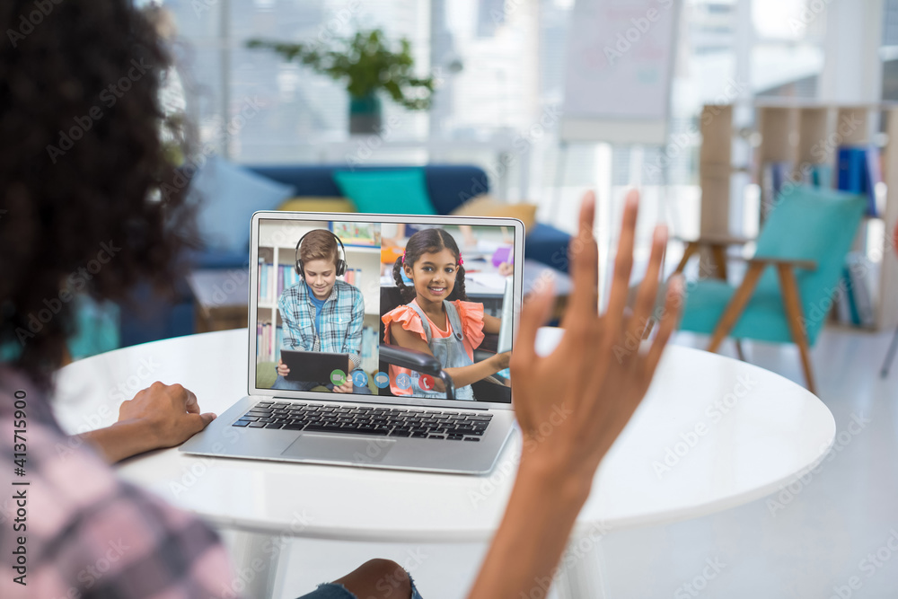 Female teacher having a video conference with male and female student on laptop at home