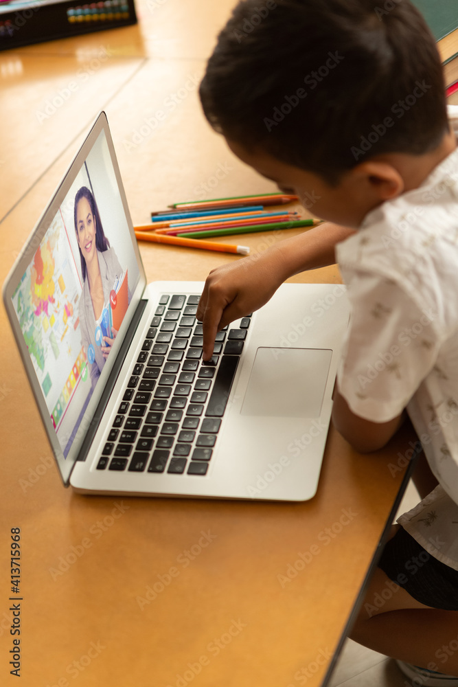 Male student having a videocall with female teacher on laptop at home