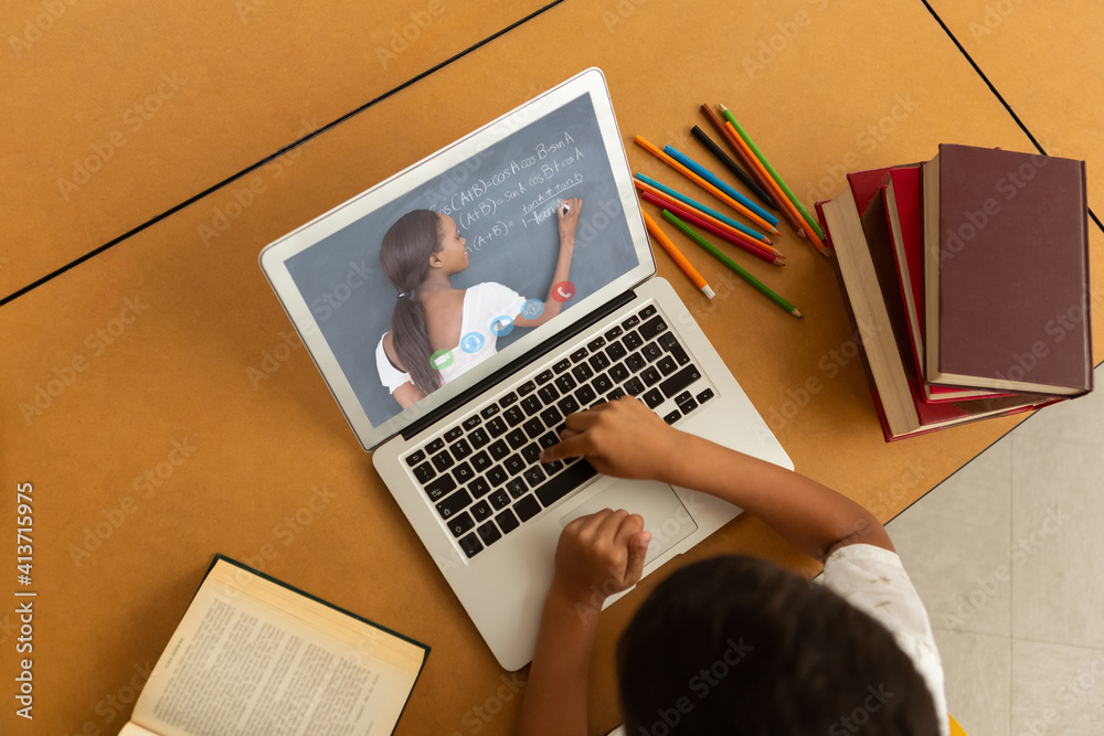 Overhead view of male student having a videocall with female teacher on laptop at home