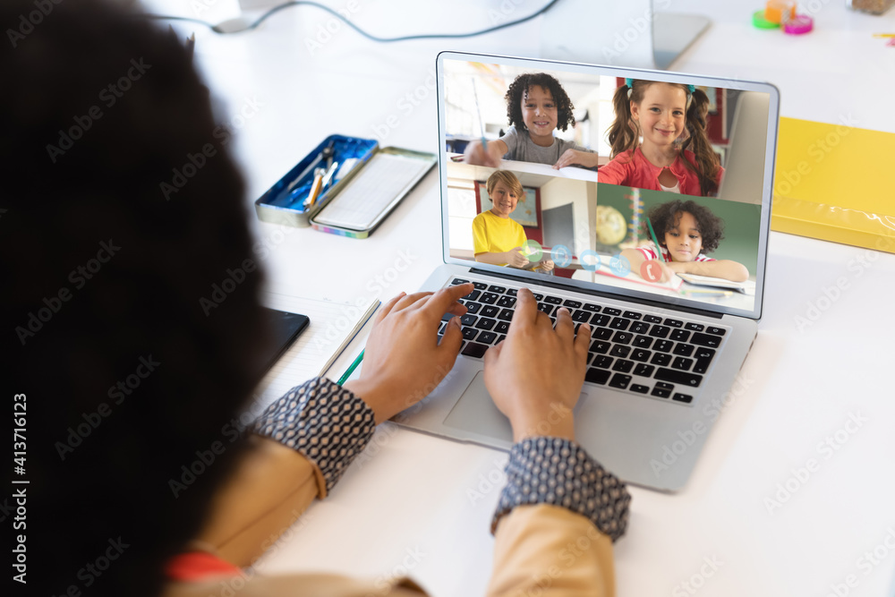 Female teacher having a video conference with multiple students on laptop at school