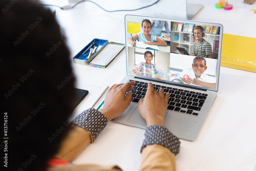 Female teacher having a video conference with multiple students on laptop at school