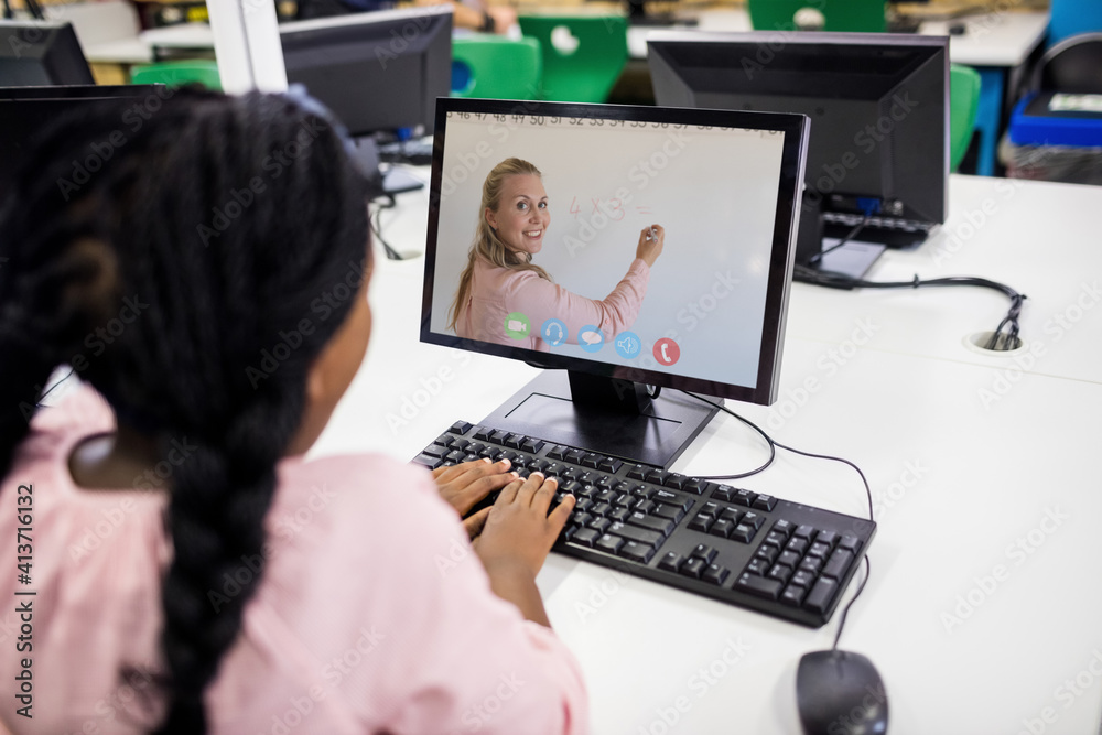 Female student having a video call with female teacher on computer at school