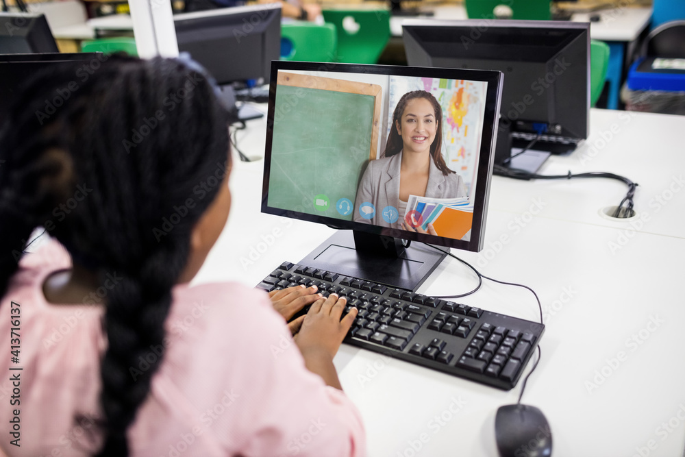 Female student having a video call with female teacher on computer at school