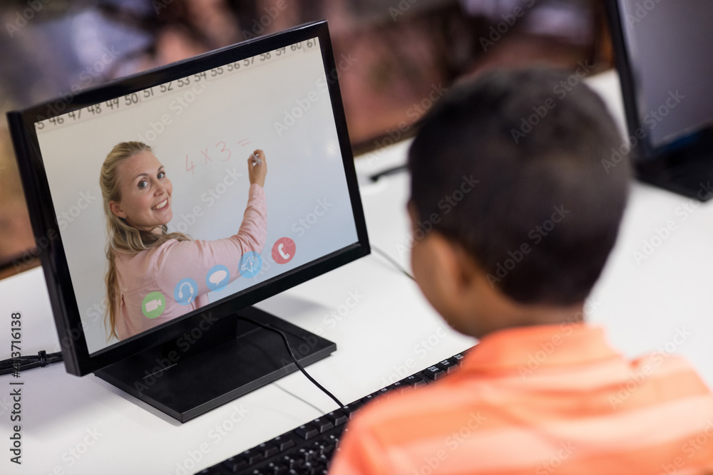 Male student having a video call with female teacher on computer at school