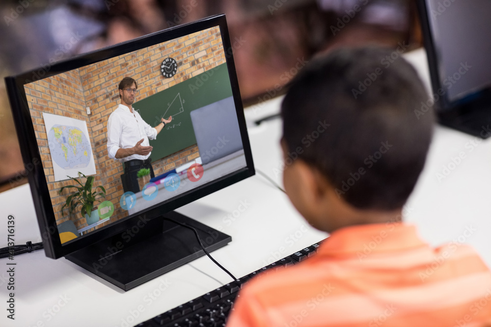 Male student having a video call with male teacher on computer at school