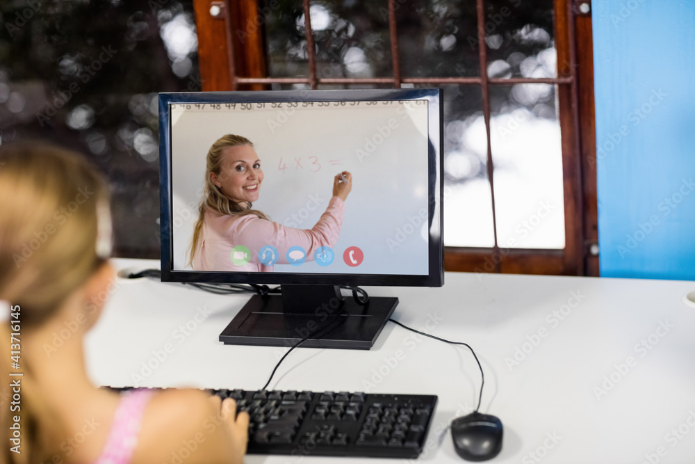 Female student having a video call with female teacher on computer at school