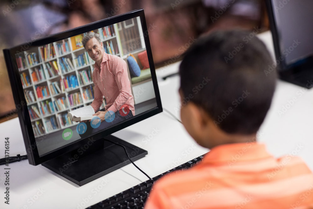 Male student having a video call with male teacher on computer at school