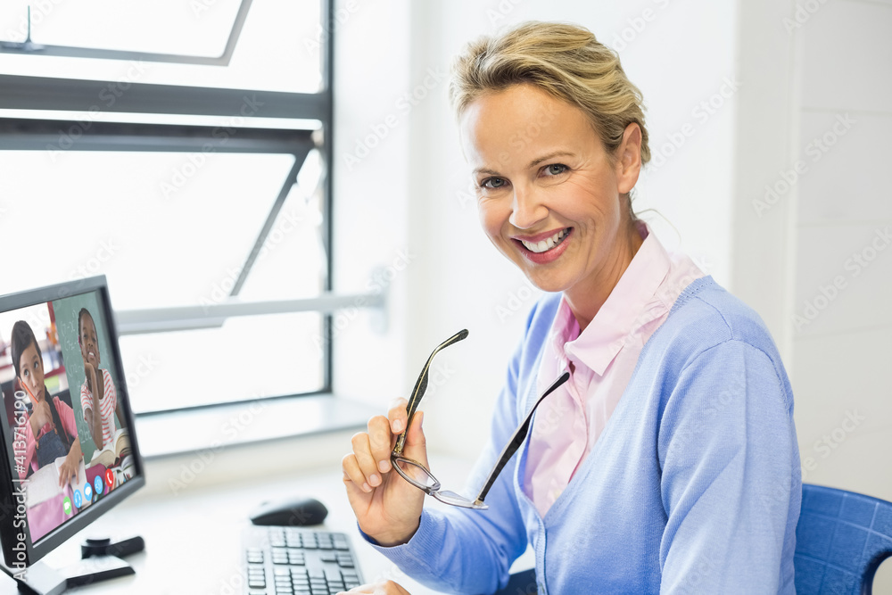 Portrait of female teacher having a video conference with multiple students on computer at school