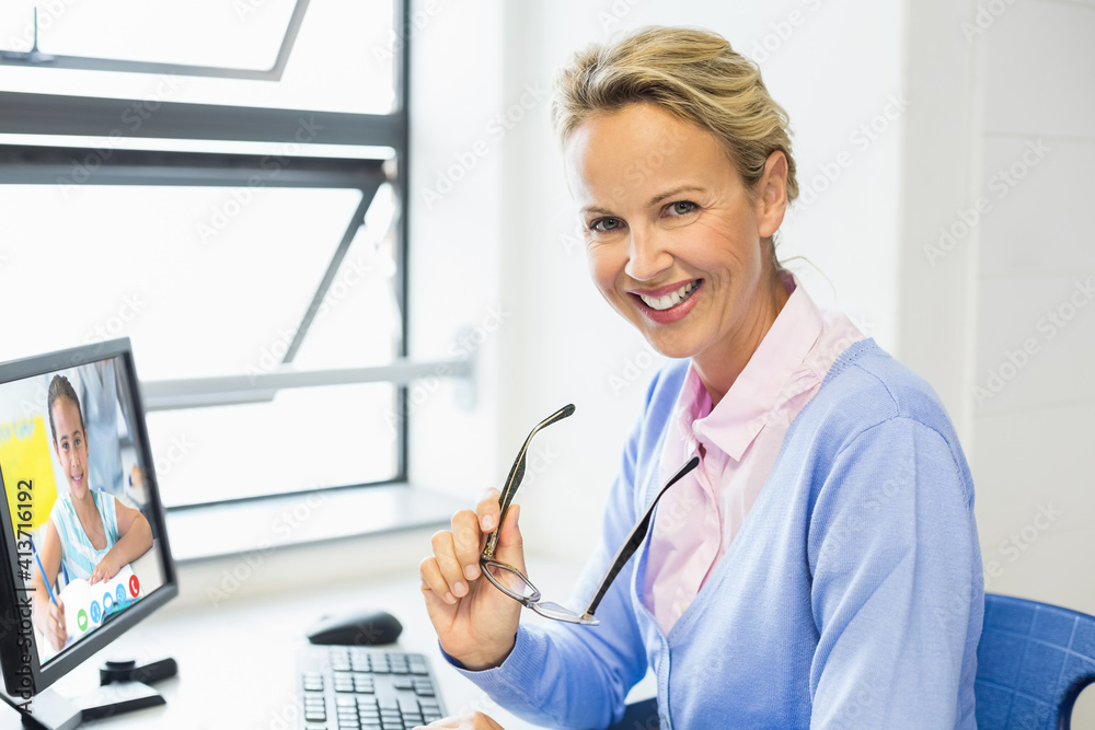 Portrait of female teacher having a video call with female student on computer at school